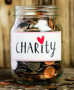 A glass bottle full of coins with a Charity and love image lable on it